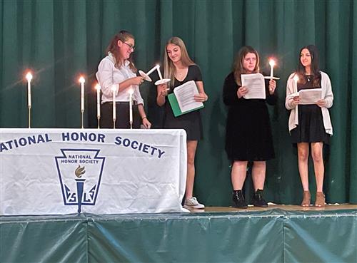 Students light candles at the Induction Ceremony