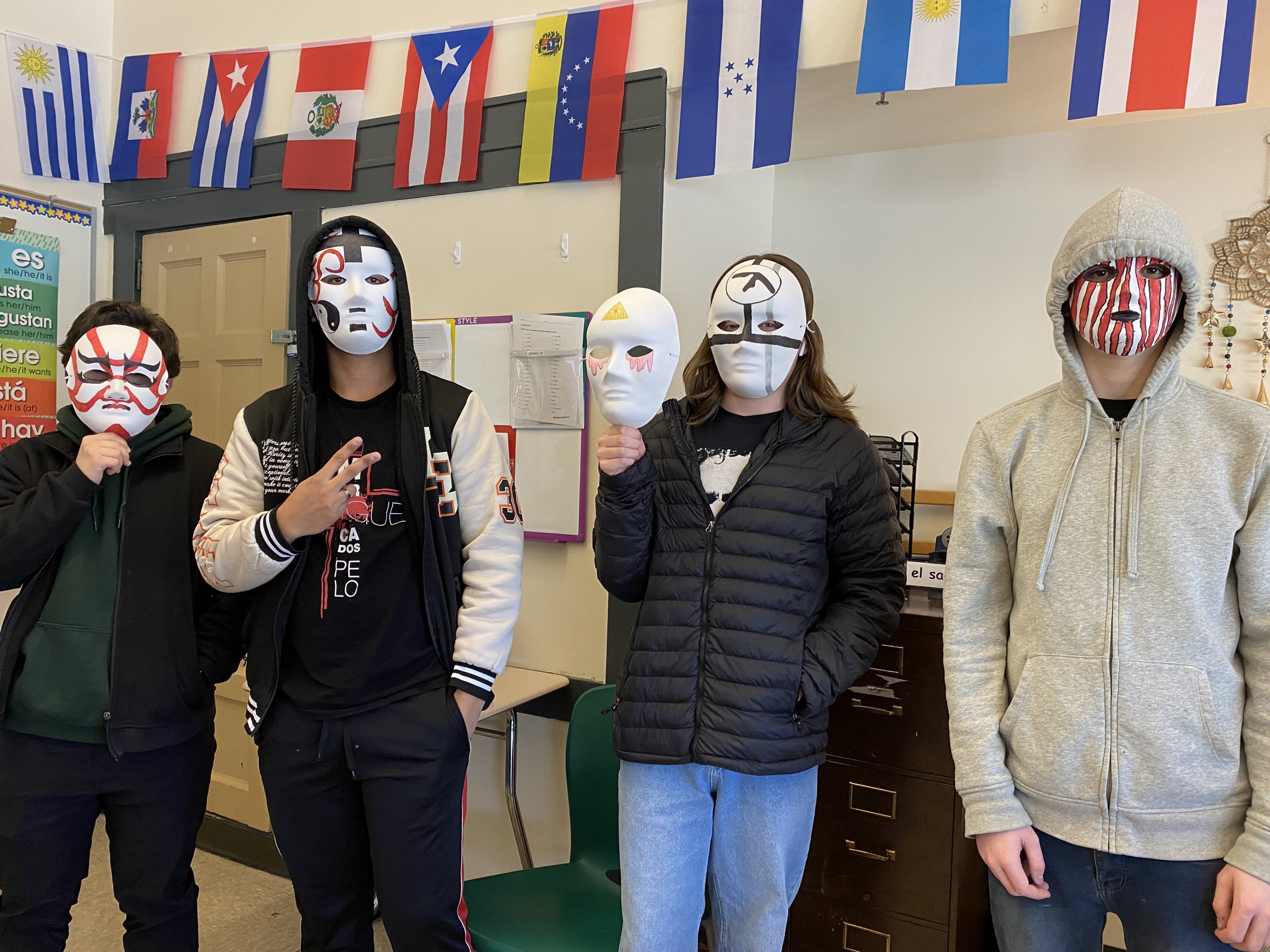 A group of students stand with masks they created.